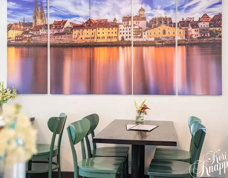 Dining table beneath European cityscape artwork